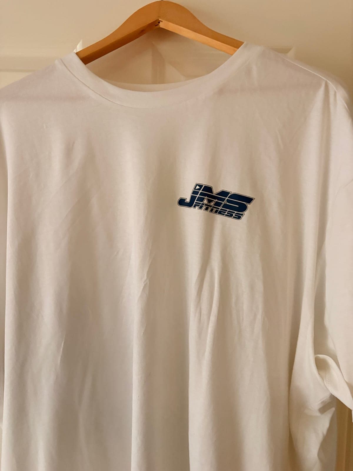 The front of the t-shirt, white with the JMS Fitness logo printed small on the left chest.