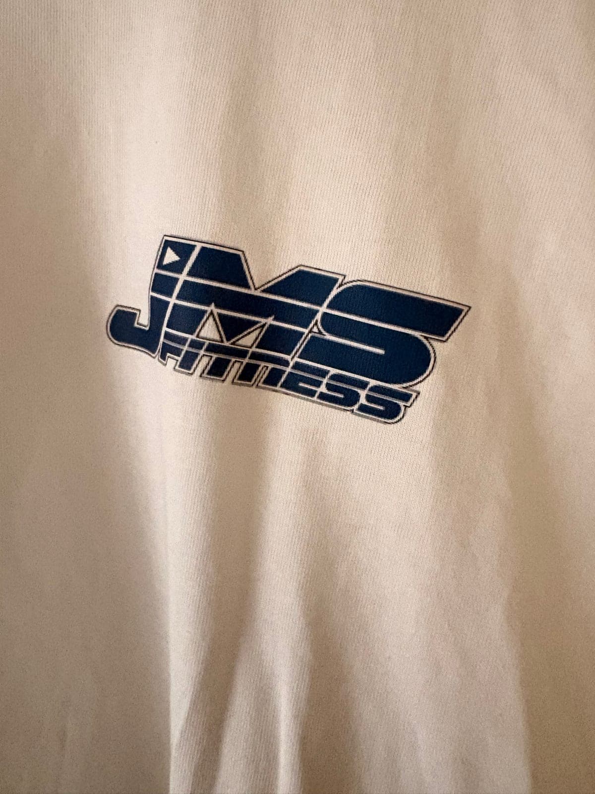 Close-up of the navy JMS Fitness logo printed on the chest.